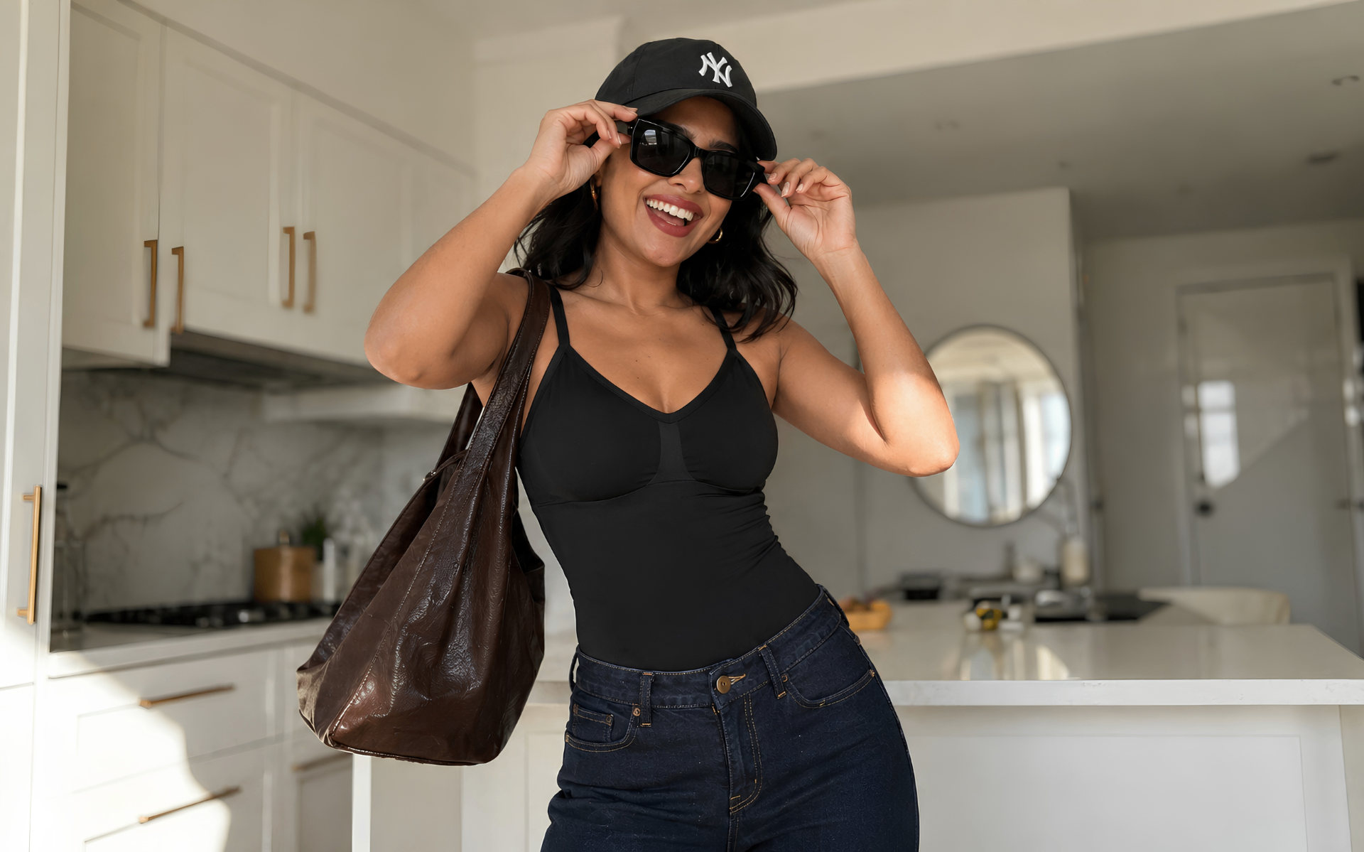 Young woman in fitted black bodysuit and high waist jeans at a sunlit cafe